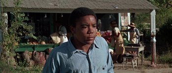 Movie still from “The Learning Tree” (1969), directed by Gordon Parks – A young man standing in front of an open air market; Medium shot, Low angle