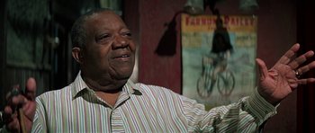 Movie still from “The Learning Tree” (1969), directed by Gordon Parks – An older man in a striped shirt is smiling; Close Up shot, Low angle