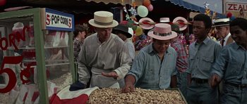 Movie still from “The Learning Tree” (1969), directed by Gordon Parks – Two men wearing hats are looking at peanuts; Medium shot, Over the shoulder angle