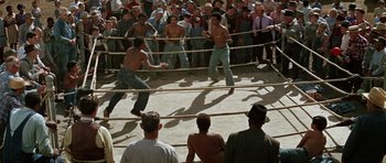 Movie still from “The Learning Tree” (1969), directed by Gordon Parks – A crowd of people watching two men boxing in a boxing ring; Wide shot, High angle