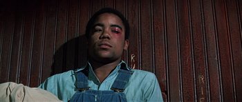Movie still from “The Learning Tree” (1969), directed by Gordon Parks – A man with a black eye and a blue shirt; Close Up shot, Low angle