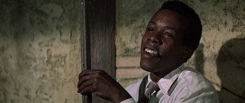 Movie still from “The Learning Tree” (1969), directed by Gordon Parks – A black man in a white dress shirt and a tie smiling; Close Up shot, Low angle