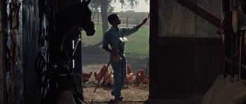 Movie still from “The Learning Tree” (1969), directed by Gordon Parks – A man standing next to a horse in a barn; Medium shot, Low angle
