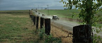 Movie still from “The Learning Tree” (1969), directed by Gordon Parks – A group of cars driving down a dirt road near barbed wire fence; Extreme Wide shot, High angle