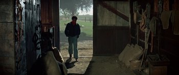 Movie still from “The Learning Tree” (1969), directed by Gordon Parks – A man standing in a barn looking out the door; Wide shot, High angle