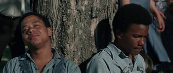Movie still from “The Learning Tree” (1969), directed by Gordon Parks – Two men are standing next to a tree; Close Up shot, High angle