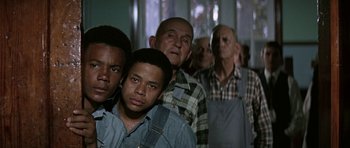 Movie still from “The Learning Tree” (1969), directed by Gordon Parks – A group of men standing next to each other in a room; Medium shot, High angle