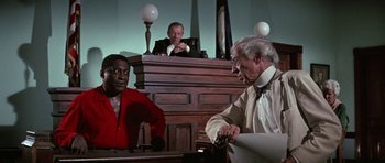 Movie still from “The Learning Tree” (1969), directed by Gordon Parks – Two men are sitting in front of a judge in a courtroom; Medium shot, High angle