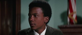 Movie still from “The Learning Tree” (1969), directed by Gordon Parks – A young man in a suit and tie looking to his left; Close Up shot, Low angle