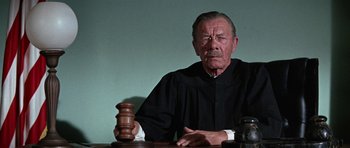 Movie still from “The Learning Tree” (1969), directed by Gordon Parks – An old man sitting at a table with a gavel in front of him; Close Up shot, Low angle