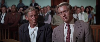 Movie still from “The Learning Tree” (1969), directed by Gordon Parks – Two men in suits sitting in front of a group of people; Close Up shot, Over the shoulder angle