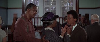 Movie still from “The Learning Tree” (1969), directed by Gordon Parks – A group of people standing next to each other in front of a window; Medium shot, Over the shoulder angle