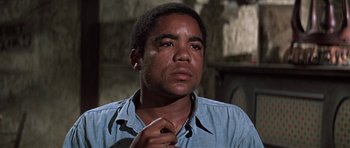 Movie still from “The Learning Tree” (1969), directed by Gordon Parks – A man in a blue shirt is looking at the camera; Close Up shot, Low angle