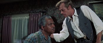 Movie still from “The Learning Tree” (1969), directed by Gordon Parks – A man is touching another man's face; Medium shot, Over the shoulder angle