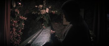 Movie still from “The Learning Tree” (1969), directed by Gordon Parks – A man sitting in front of a couch with a bouquet of flowers; Medium shot, High angle
