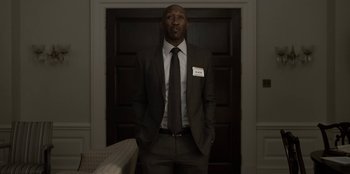 Movie still from “House of Cards” (2013), created by Beau Willimon – A man in a suit and tie standing in front of a door; Medium shot, Low angle