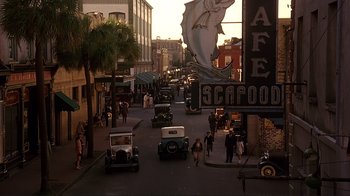 Movie still from “The Legend of Bagger Vance” (2000), directed by Robert Redford – A street scene with many cars on the side of the road; Extreme Wide shot, High angle