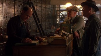 Movie still from “The Legend of Bagger Vance” (2000), directed by Robert Redford – Two men sitting at a desk in front of a wooden table; Medium shot, Low angle