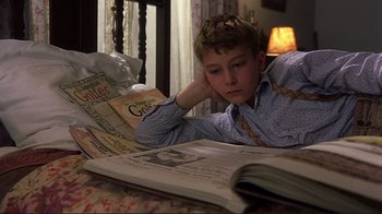 Movie still from “The Legend of Bagger Vance” (2000), directed by Robert Redford – A young boy is reading a book in bed; Close Up shot, High angle
