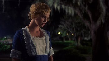 Movie still from “The Legend of Bagger Vance” (2000), directed by Robert Redford – A woman in a blue and white dress standing in front of a tree; Medium shot, Low angle