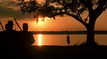 Movie still from “The Legend of Bagger Vance” (2000), directed by Robert Redford – Two people standing under a tree watching the sun go down; Extreme Wide shot, Over the shoulder angle