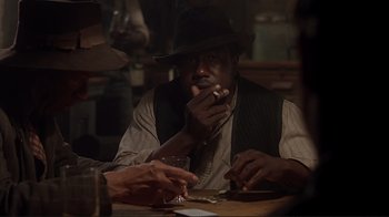 Movie still from “The Legend of Bagger Vance” (2000), directed by Robert Redford – A man sitting at a table smoking a cigarette; Medium shot, Over the shoulder angle