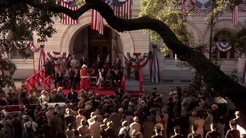 Movie still from “The Legend of Bagger Vance” (2000), directed by Robert Redford – A crowd of people sitting in front of a building; Extreme Wide shot, High angle
