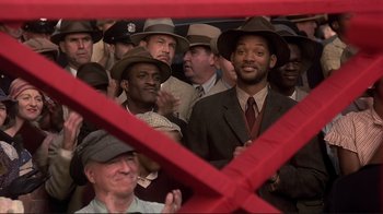 Movie still from “The Legend of Bagger Vance” (2000), directed by Robert Redford – A group of men in suits and hats in front of a crowd of onlookers; Medium shot, Low angle