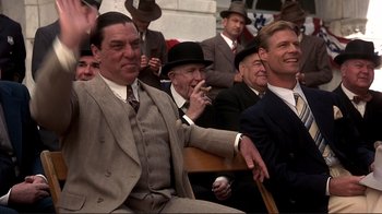 Movie still from “The Legend of Bagger Vance” (2000), directed by Robert Redford – A group of men in suits and hats sitting in a crowd; Medium shot, Low angle