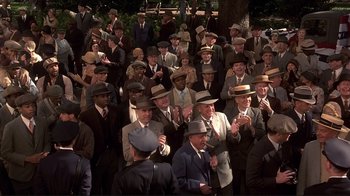 Movie still from “The Legend of Bagger Vance” (2000), directed by Robert Redford – A group of men in suits and hats clapping in front of a crowd of onlookers; Wide shot, High angle