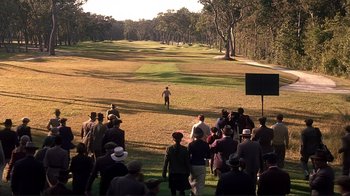 Movie still from “The Legend of Bagger Vance” (2000), directed by Robert Redford – A group of people standing in a grassy field; Extreme Wide shot, High angle