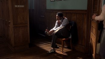 Movie still from “The Legend of Bagger Vance” (2000), directed by Robert Redford – A man sitting on a wooden chair in a room; Wide shot, High angle