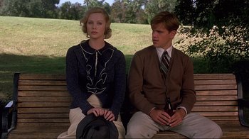 Movie still from “The Legend of Bagger Vance” (2000), directed by Robert Redford – A man and a woman sitting on a wooden bench; Medium shot, Low angle