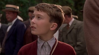 Movie still from “The Legend of Bagger Vance” (2000), directed by Robert Redford – A young boy wearing a red sweater looks upward; Close Up shot, Low angle