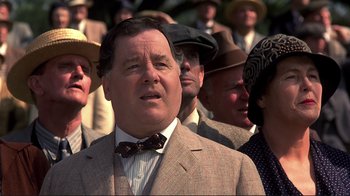 Movie still from “The Legend of Bagger Vance” (2000), directed by Robert Redford – A man in a suit and bow tie standing in a crowd of people; Close Up shot, Low angle