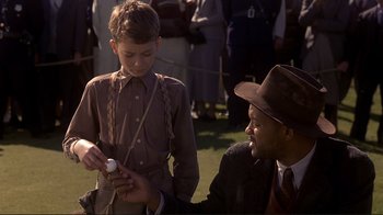 Movie still from “The Legend of Bagger Vance” (2000), directed by Robert Redford – A young boy and an older man are looking at a cell phone; Medium shot, Over the shoulder angle