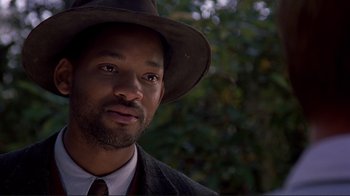 Movie still from “The Legend of Bagger Vance” (2000), directed by Robert Redford – A person wearing a hat with trees in the background; Close Up shot, Over the shoulder angle