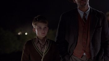 Movie still from “The Legend of Bagger Vance” (2000), directed by Robert Redford – A man and a young boy standing next to each other in the dark; Medium shot, Over the shoulder angle