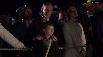 Movie still from “The Legend of Bagger Vance” (2000), directed by Robert Redford – A group of people standing around a young boy; Medium shot, Low angle