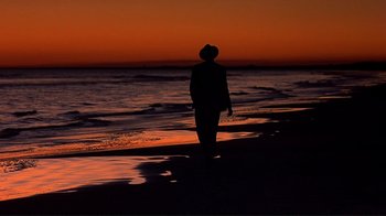Movie still from “The Legend of Bagger Vance” (2000), directed by Robert Redford – A person standing on the beach at sunset; Wide shot, Low angle