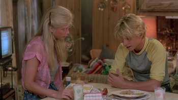 Movie still from “The Legend of Billie Jean” (1985), directed by Matthew Robbins – A couple of people sitting at a table with food; Medium shot, Over the shoulder angle