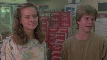 Movie still from “The Legend of Billie Jean” (1985), directed by Matthew Robbins – A couple of people standing next to each other in a room; Medium shot, Over the shoulder angle