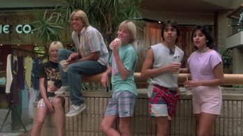 Movie still from “The Legend of Billie Jean” (1985), directed by Matthew Robbins – A group of young men sitting on a wall eating ice cream; Wide shot, Low angle