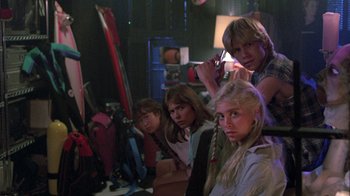 Movie still from “The Legend of Billie Jean” (1985), directed by Matthew Robbins – A group of young people standing next to each other in a room; Medium shot, Low angle
