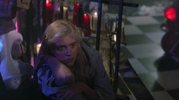 Movie still from “The Legend of Billie Jean” (1985), directed by Matthew Robbins – A woman sitting on a chair in front of candles; Medium shot, High angle