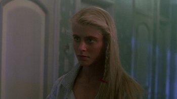 Movie still from “The Legend of Billie Jean” (1985), directed by Matthew Robbins – A woman with long blonde hair standing in front of a wall; Close Up shot, Over the shoulder angle
