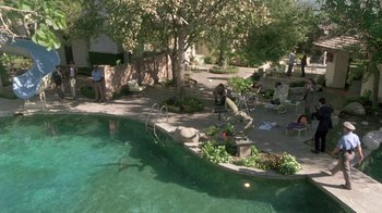Movie still from “The Legend of Billie Jean” (1985), directed by Matthew Robbins – A pool area with people sitting on the side of the pool; Extreme Wide shot, High angle