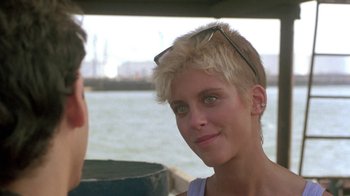 Movie still from “The Legend of Billie Jean” (1985), directed by Matthew Robbins – A young woman with blonde hair wearing glasses and smiling; Close Up shot, Over the shoulder angle