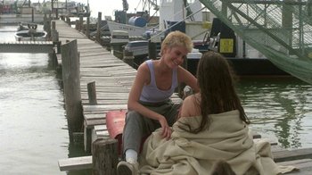 Movie still from “The Legend of Billie Jean” (1985), directed by Matthew Robbins – Two women sitting on a dock next to a body of water; Medium shot, Over the shoulder angle