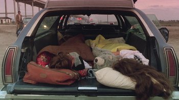 Movie still from “The Legend of Billie Jean” (1985), directed by Matthew Robbins – A car trunk filled with many blankets and pillows; Wide shot, High angle